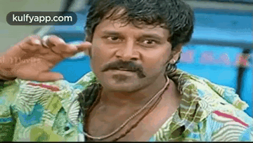A Man With A Mustache Is Making A Funny Face While Wearing A Colorful Shirt . GIF