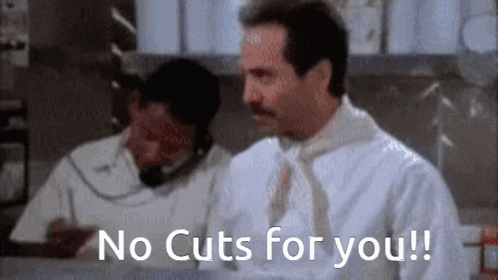 A Man With A Mustache Is Sitting At A Counter Talking On A Phone And Says `` No Cuts For You ! '' GIF