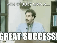 A Man With A Mustache Is Sitting At A Desk With The Words `` Great Success '' Written On It . GIF