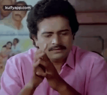 A Man With A Mustache Is Sitting At A Table With His Hands Folded In Front Of Him . GIF