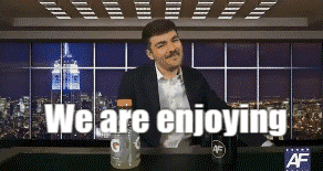 A Man With A Mustache Is Sitting At A Table With The Words " We Are Enjoying " Above Him GIF