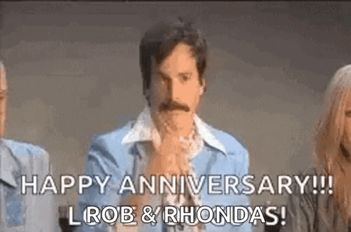 A Man With A Mustache Is Sitting In Front Of A Group Of People And Says `` Happy Anniversary ! `` GIF