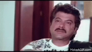 A Man With A Mustache Is Sitting In Front Of A Window And Looking At The Camera . GIF