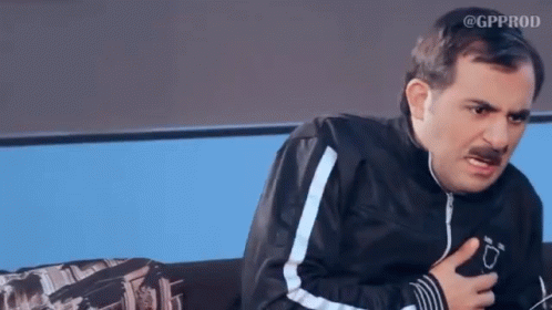A Man With A Mustache Is Sitting On A Couch And Making A Funny Face GIF