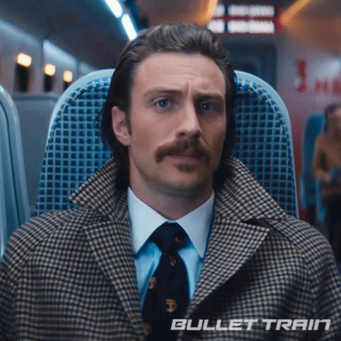 a man with a mustache is sitting on a train with the words " bullet train " on the bottom