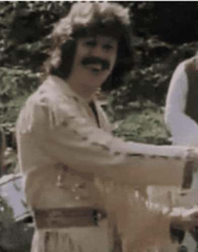 A Man With A Mustache Is Smiling And Holding A Glass Of Wine GIF
