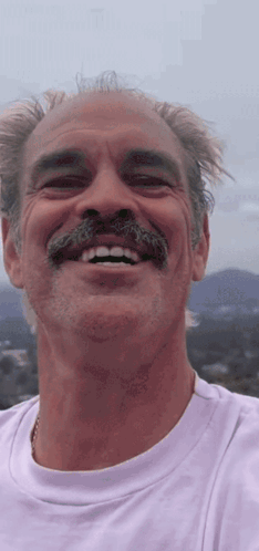 A Man With A Mustache Is Smiling And Wearing A Purple Shirt GIF
