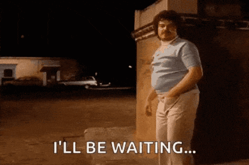 A Man With A Mustache Is Standing In Front Of A Building And Saying I 'Ll Be Waiting GIF