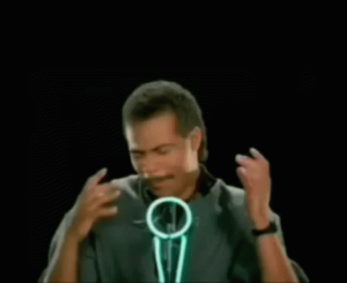 A Man With A Mustache Is Standing In Front Of A Microphone With The Words Bustin ' Makes Me In Green Letters . GIF