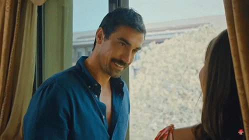 A Man With A Mustache Is Standing In Front Of A Window With A Woman GIF