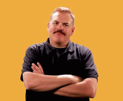 A Man With A Mustache Is Standing With His Arms Crossed In Front Of A Yellow Background GIF