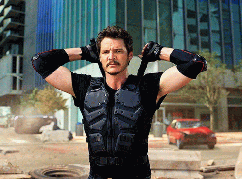 A Man With A Mustache Is Standing With His Hands Behind His Head In Front Of A Building GIF