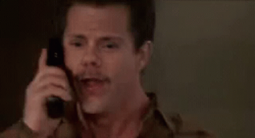 A Man With A Mustache Is Talking On A Cell Phone . GIF