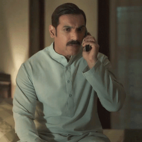 A Man With A Mustache Is Talking On A Cellphone GIF