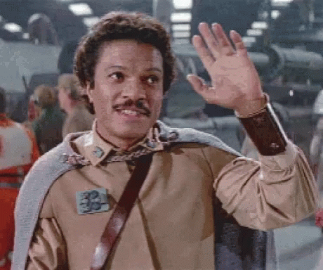 A Man With A Mustache Is Waving His Hand In Front Of A Crowd Of People . GIF