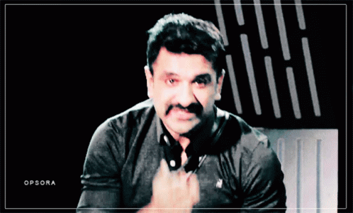 A Man With A Mustache Is Wearing A Black Polo Shirt With A White Horse On It GIF