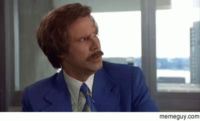 A Man With A Mustache Is Wearing A Blue Suit And Tie And Making A Funny Face . GIF