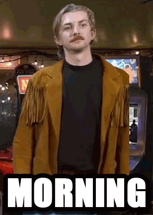 A Man With A Mustache Is Wearing A Brown Jacket And Standing In Front Of An Arcade Machine That Says Morning . GIF