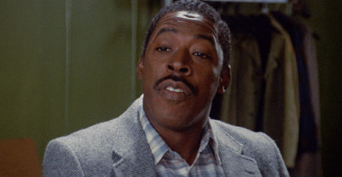 A Man With A Mustache Is Wearing A Grey Jacket And A Plaid Shirt GIF