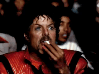 A Man With A Mustache Is Wearing A Michael Jackson Costume While Sitting In Front Of A Crowd . GIF