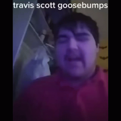 A Man With A Mustache Is Wearing A Red Shirt And Has The Name Travis Scott Goosebumps On His Face GIF