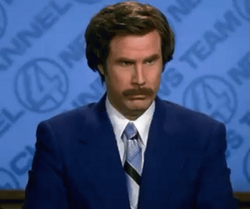 A Man With A Mustache Is Wearing A Suit And Tie GIF