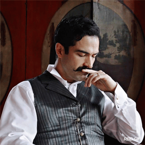 a man with a mustache is wearing a white shirt and a grey vest