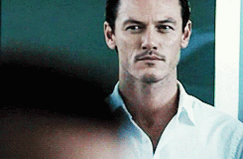 A Man With A Mustache Is Wearing A White Shirt And Looking At The Camera With A Serious Look On His Face . GIF