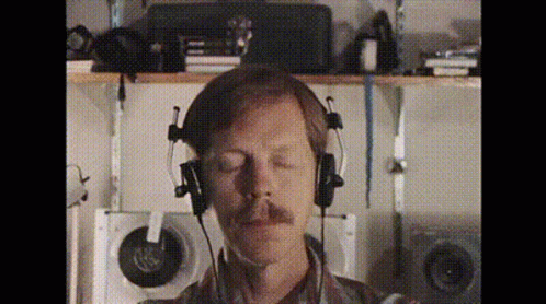 A Man With A Mustache Is Wearing Headphones With His Eyes Closed GIF
