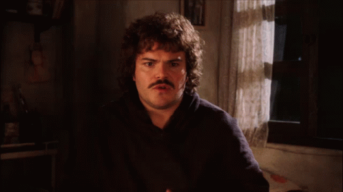 a man with a mustache says " let 's get down to the nitty gritty " in front of a window
