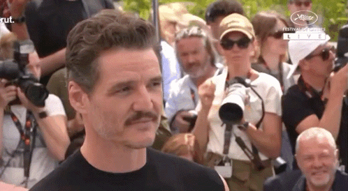 A Man With A Mustache Stands In Front Of A Crowd Of People . GIF