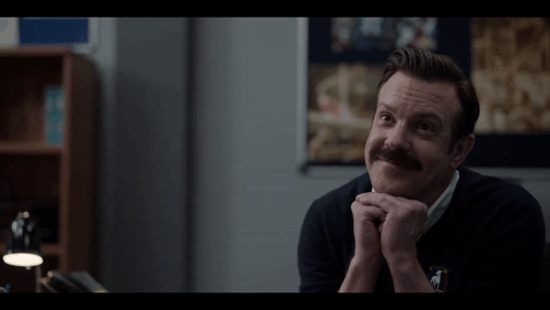 A Man With A Mustache Wearing A Black Sweater With A Horse On It GIF