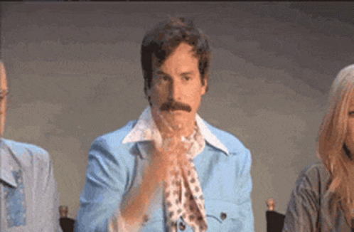 A Man With A Mustache Wearing A Blue Jacket And Scarf Is Clapping His Hands GIF