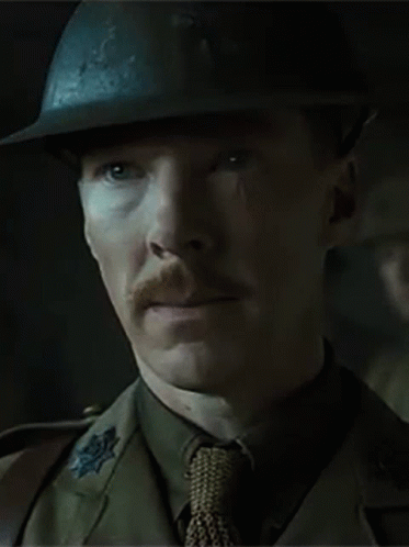 A Man With A Mustache Wearing A Helmet And Tie Is Looking At The Camera . GIF