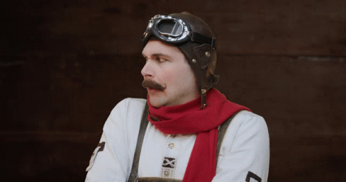 A Man With A Mustache Wearing A Red Scarf And A Helmet GIF