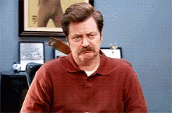 A Man With A Mustache Wearing A Red Shirt Is Sitting At A Table GIF