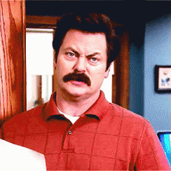 A Man With A Mustache Wearing A Red Shirt Looks At The Camera GIF