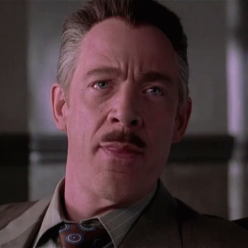 A Man With A Mustache Wearing A Suit And Tie Is Looking At The Camera GIF