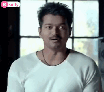 A Man With A Mustache Wearing A White Shirt Is Standing In Front Of A Window . GIF