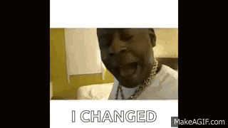 a man with a necklace on his neck is sitting on a bed and saying `` i changed '' .