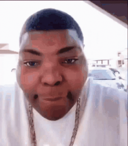 A Man With A Nose Ring Is Making A Funny Face While Wearing A White Shirt And A Chain . GIF