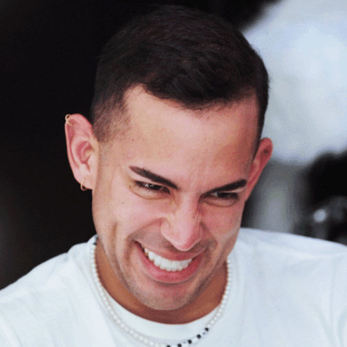 A Man With A Pearl Necklace Around His Neck Smiles For The Camera GIF