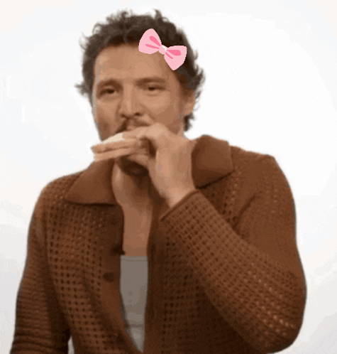A Man With A Pink Bow On His Head Eating A Sandwich GIF