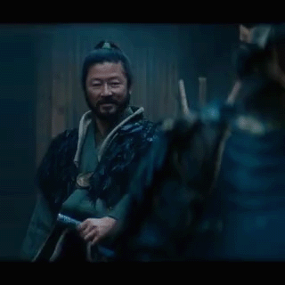 a man with a ponytail and a beard is wearing a black coat