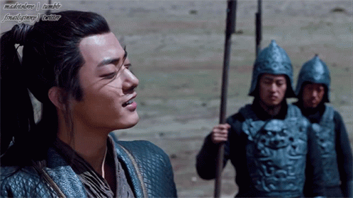 A Man With A Ponytail Is Standing In Front Of A Group Of Soldiers With Their Helmets On GIF