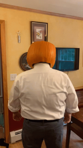 A Man With A Pumpkin On His Head In Front Of A Tv GIF