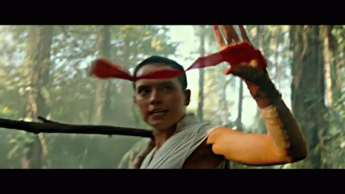 A Man With A Red Headband Is Holding A Stick In The Woods GIF