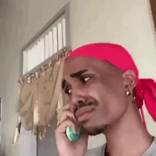 A Man With A Red Headband Is Talking On A Cell Phone . GIF