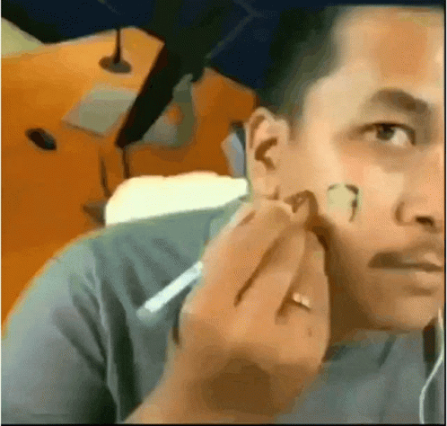 A Man With A Ring On His Finger Is Applying Makeup To His Face . GIF