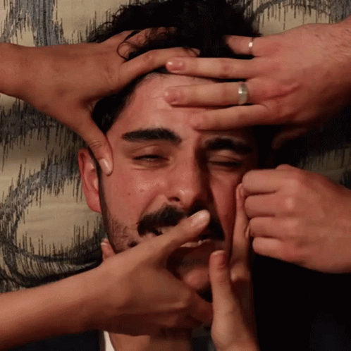 A Man With A Ring On His Finger Is Being Squeezed By Several People GIF